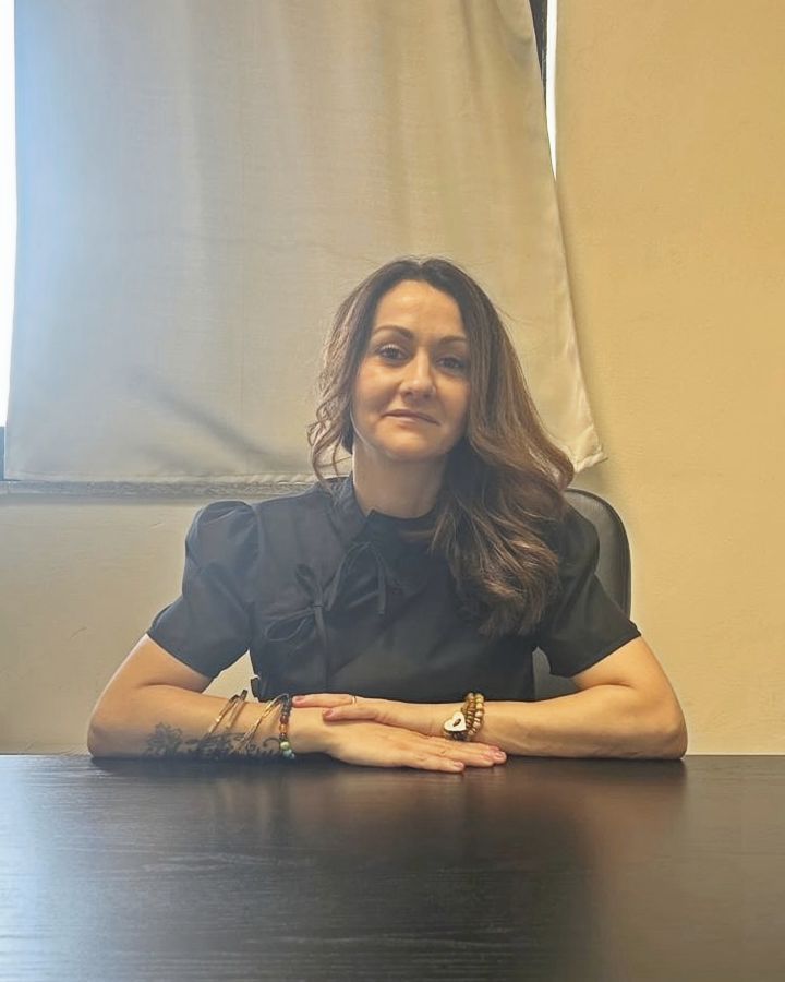 Ritratto di Daisy Ghiglioni seduta alla scrivania, con le mani appoggiate sul piano.